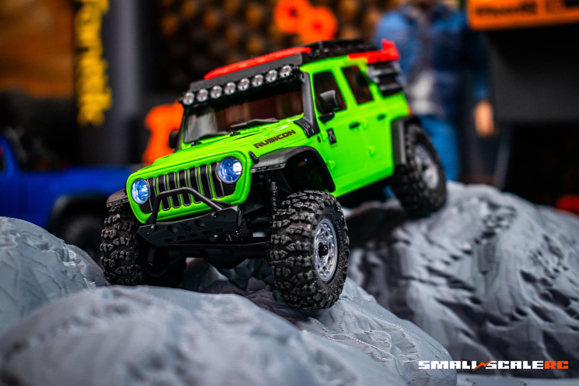 Off-road green RC truck with rugged tires and LED lights for scale modeling.