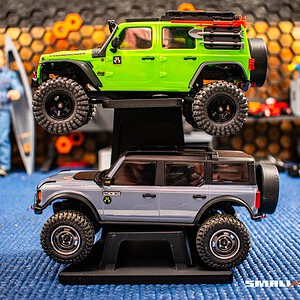 RC cars on slanted double-decker display stand for small-scale models.
