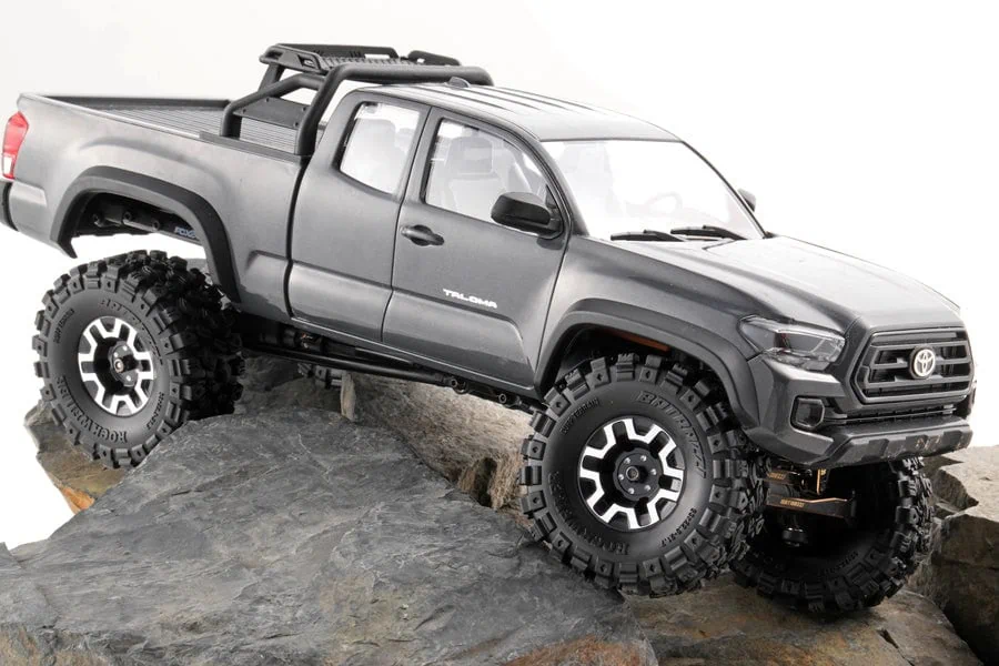 Detailed image of a small-scale RC off-road truck on rocky terrain.