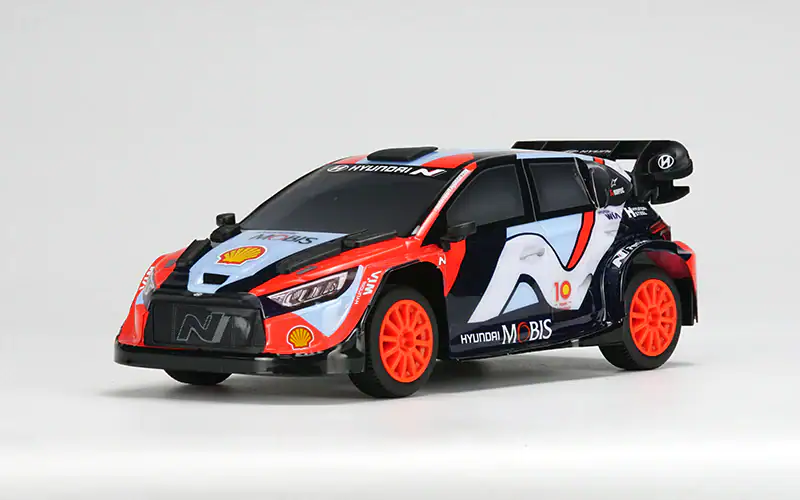Small-scale RC Hyundai i20 WRC rally car with detailed design and bright orange wheels.