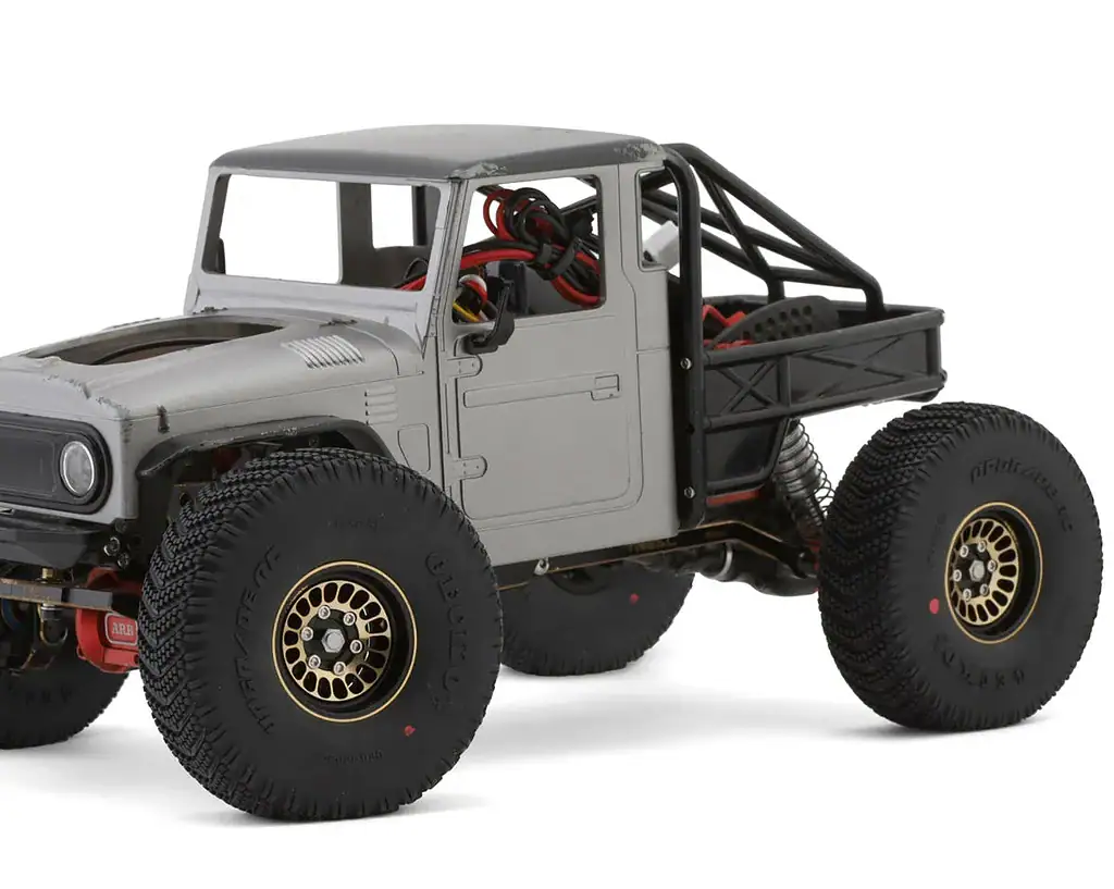 Small-scale RC off-road truck with large tires and detailed chassis for hobby enthusiasts.